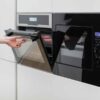 کابینت آشپزخانه نیکلند، نمای نزدیک فر توکار مشکی در حال باز شدن